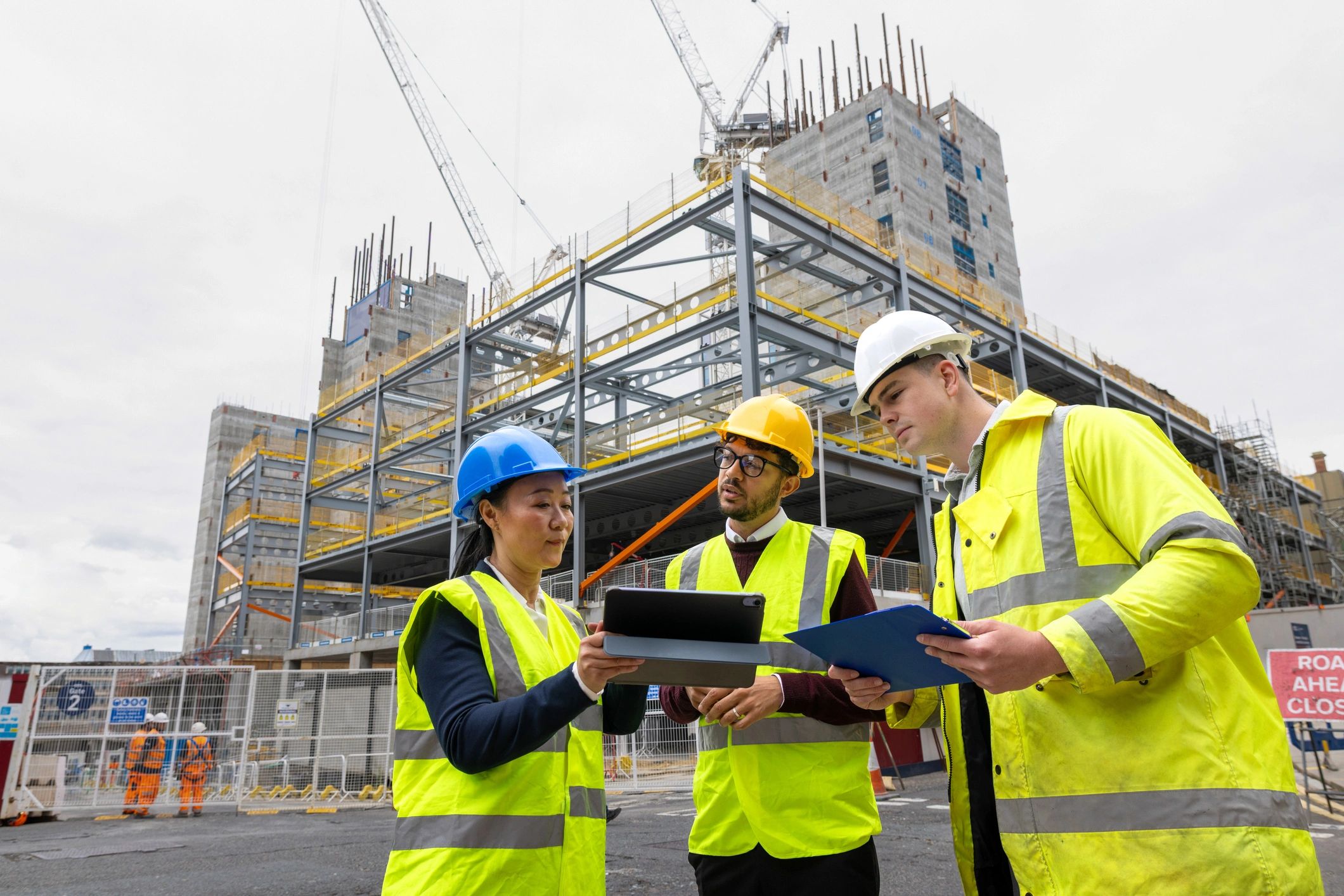 Profesionales de construcción revisando planos en una obra con fondo claro